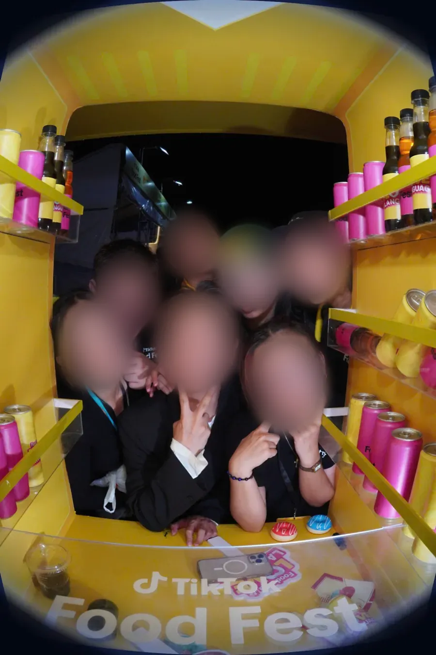 Ảnh nhóm bạn chụp trong trạm photobooth TryOh! tại TikTok Food Fest, khung vàng có kệ lon nước và logo sự kiện